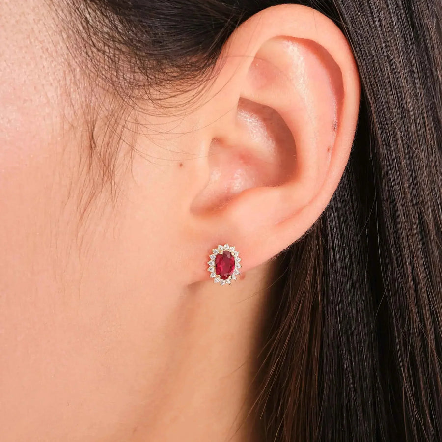 Gros plan d'une puce d'oreille halo rubis de synthèse en or 14 carats portée au lobe de l'oreille