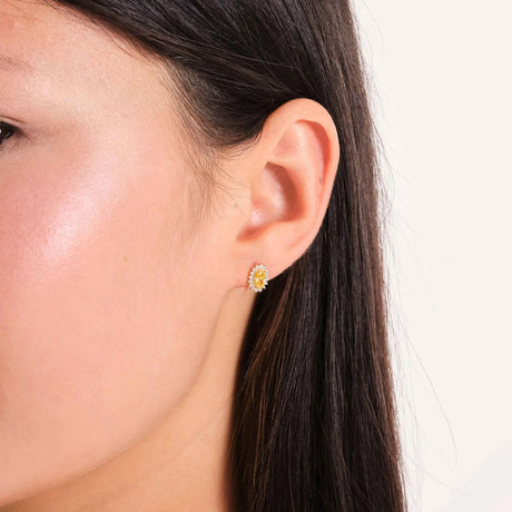 Gros plan d'une puce d'oreille halo citrine de synthèse en or jaune 14 carats portée au lobe de l'oreille