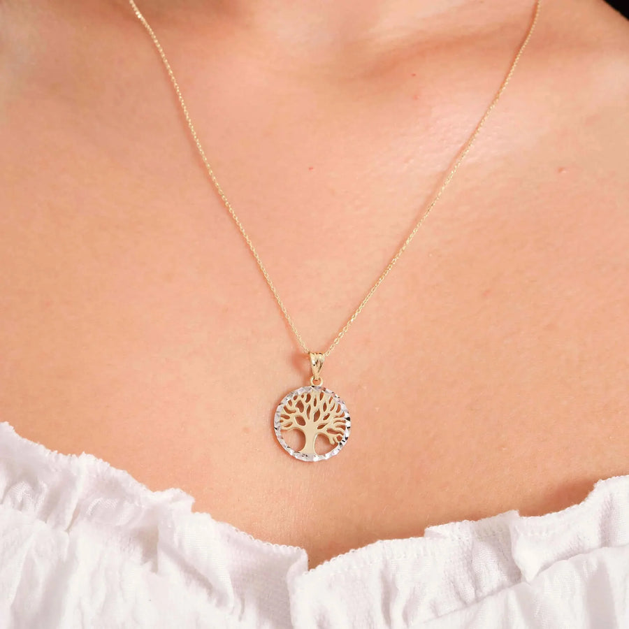 Collier pendentif arbre de vie bicolore en or 14 carats porté au cou avec un haut blanc à volants
