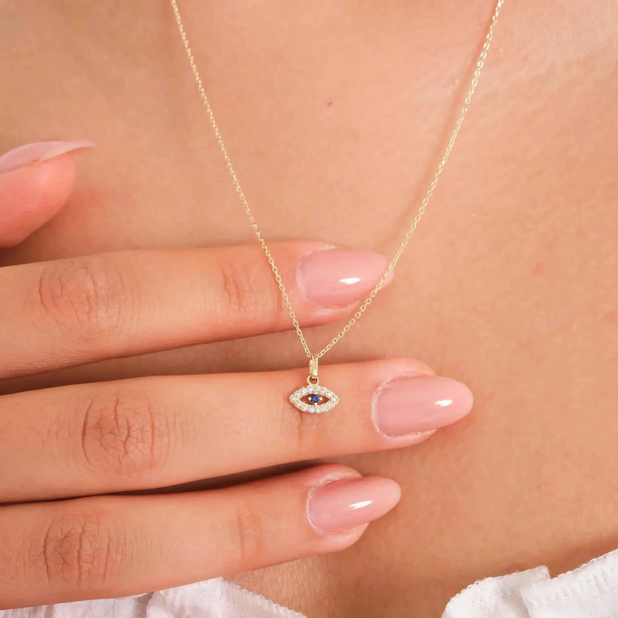 Collana occhio turco in oro giallo 14kt con zaffiro blu creato in laboratorio, indossata e tenuta tra le dita