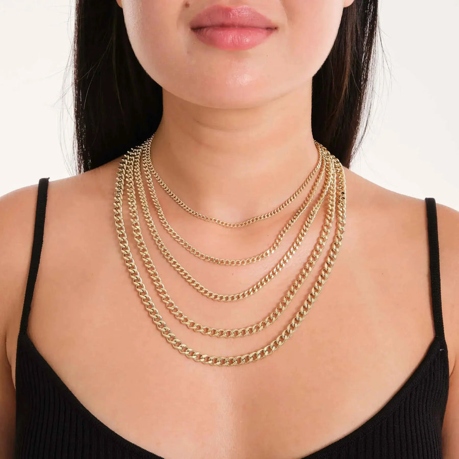 Cadenas cubanas Miami en oro amarillo de 14 quilates superpuestas en la modelo con top negro