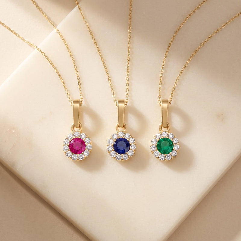 Colliers pendentif halo rubis, saphir et émeraude de synthèse en or 14 carats sur une dalle de pierre ivoire