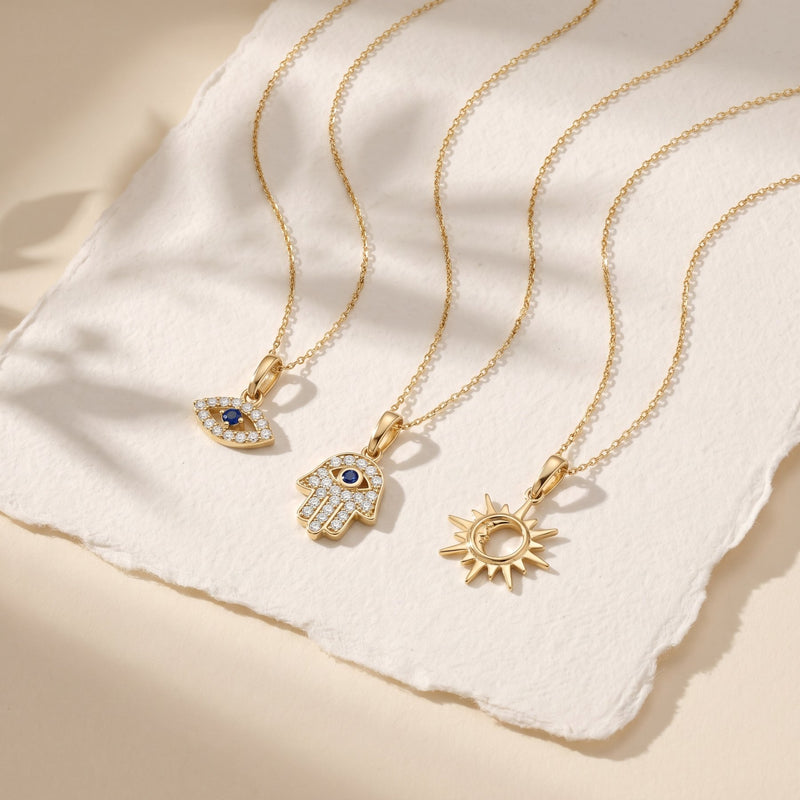 Colliers pendentif mauvais œil, main hamsa et soleil et lune en or 14 carats sur du papier coton