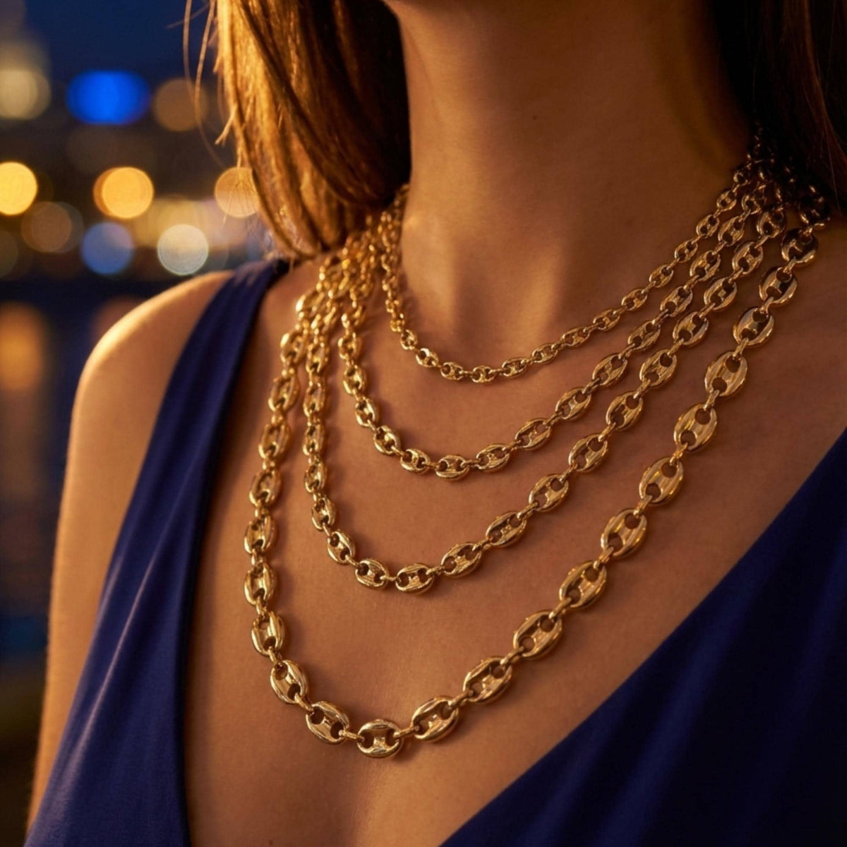 Collane a maglia marina in oro giallo 14kt indossate a strati dalla modella con abito blu navy