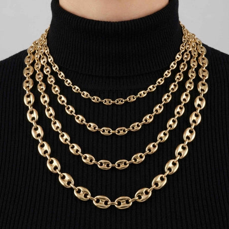 Colliers chaîne maille marine en or jaune 14 carats en quatre largeurs superposés sur un col roulé noir