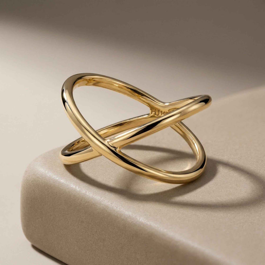 Bague infini entrecroisée en or jaune 14 carats posée debout sur le bord d'un bloc de pierre