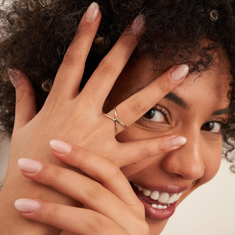 Mannequin regardant entre ses doigts, portant une bague infini entrecroisée en or 14 carats