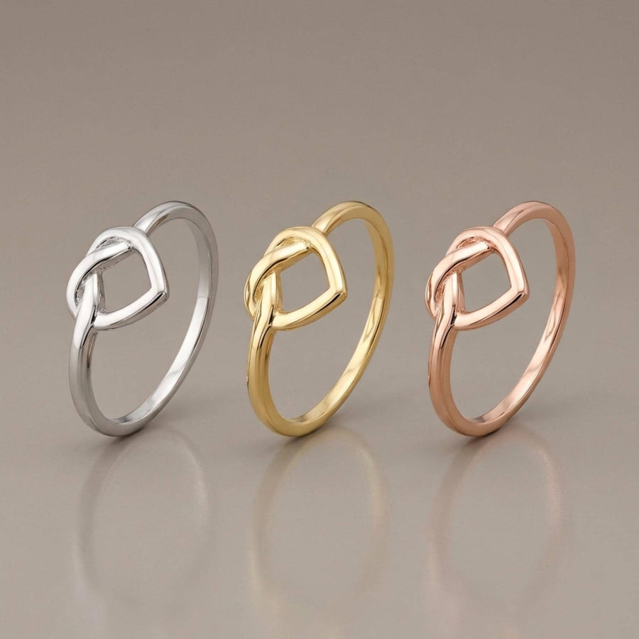 Anelli aperti con cuore infinito in oro giallo, bianco e rosa 14kt in piedi su sfondo grigio
