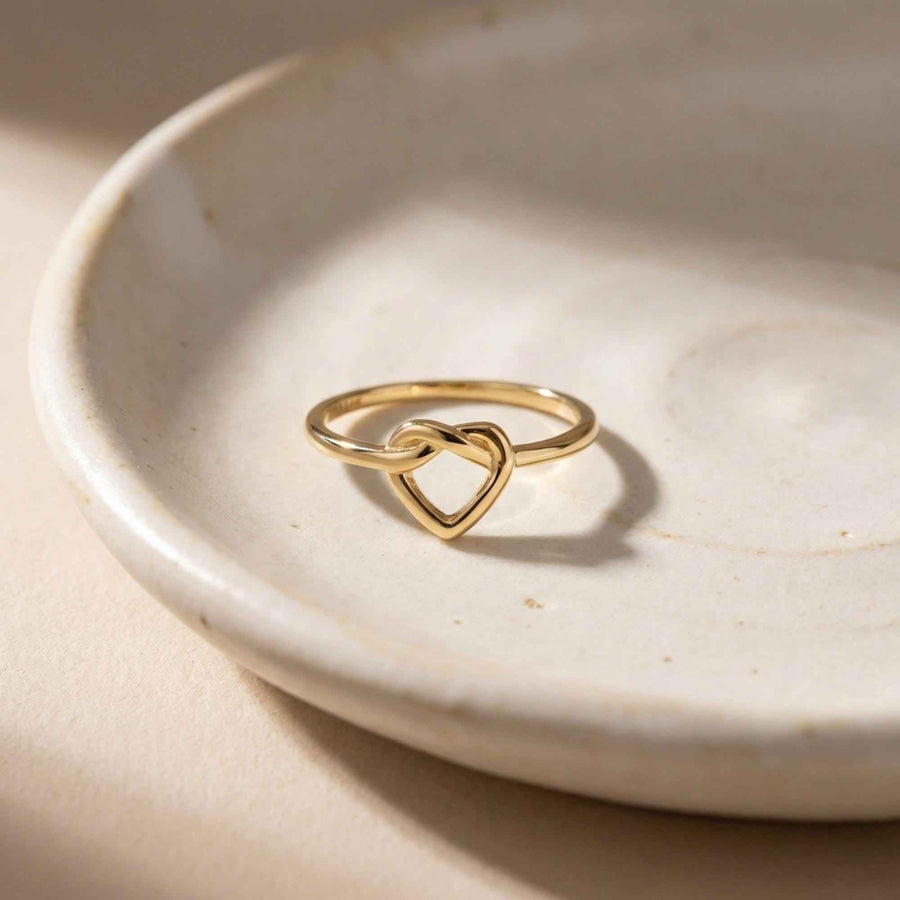Anello aperto con cuore infinito in oro giallo 14kt adagiato in un piattino di ceramica bianca