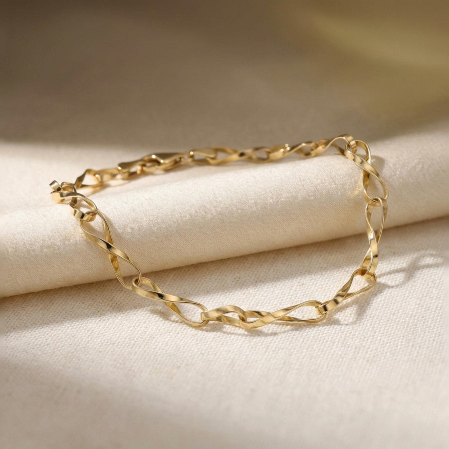 Pulsera de cadena retorcida de eslabones infinito en oro amarillo de 14 quilates sobre lino doblado