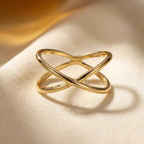 Gros plan de la bague infini entrecroisée en or jaune 14 carats sur une surface crème