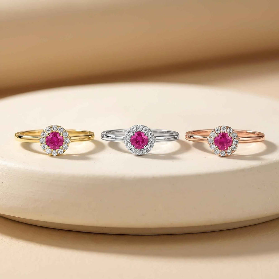 Bagues fines halo rubis de synthèse en or jaune, blanc et rose 14 carats côte à côte sur une coupelle de présentation