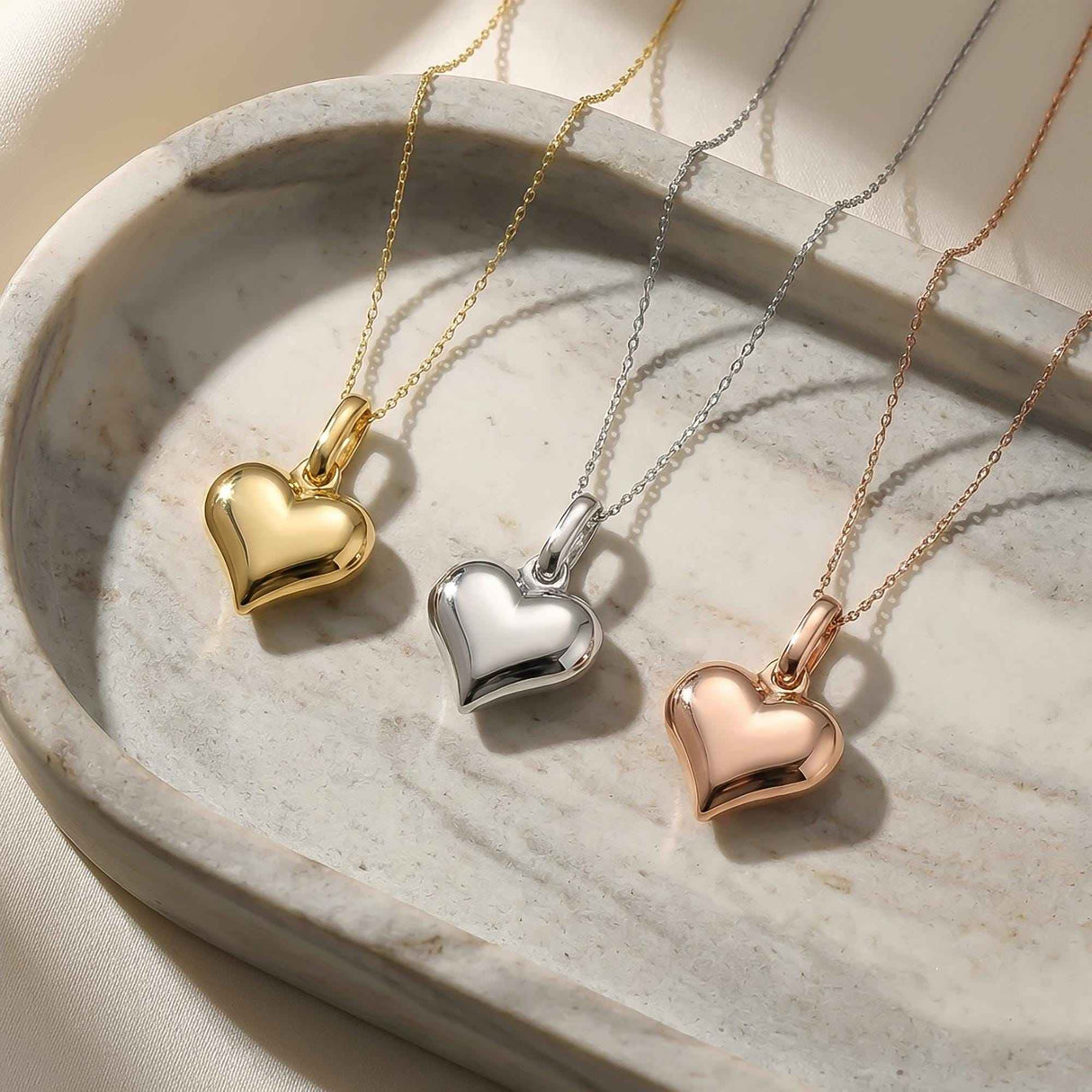 14K yellow, white and rose gold puffed heart necklaces in an oval stone dish