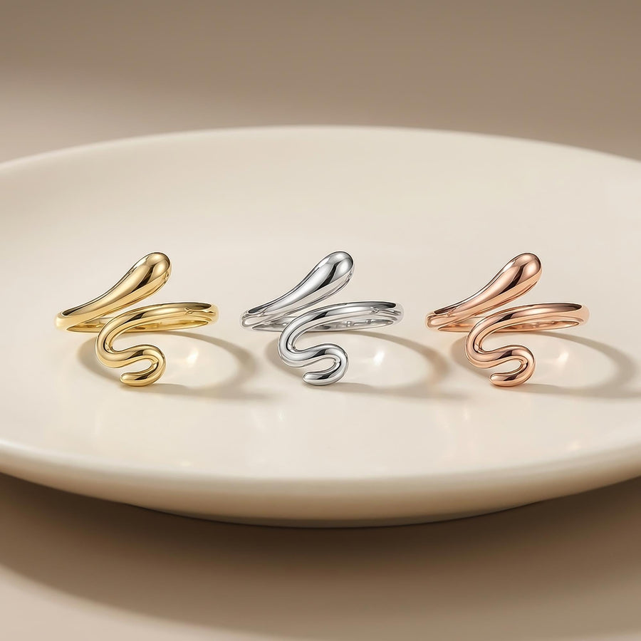 Anillos abiertos de serpiente envolvente en oro amarillo, blanco y rosa de 14 quilates alineados sobre un plato blanco