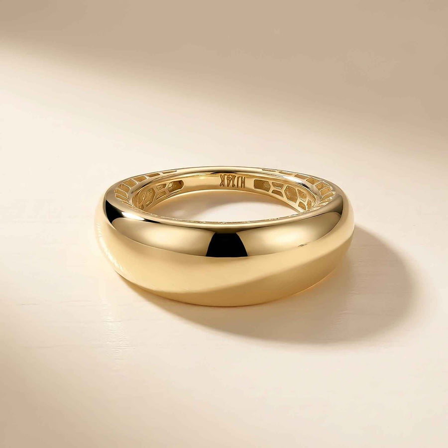 Anillo cúpula ancho en oro amarillo de 14 quilates sobre fondo crema, vista lateral con el interior grabado
