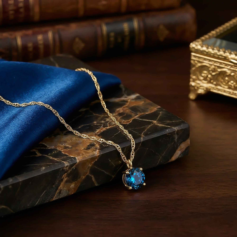 London-Blue-Topas-Solitärhalskette aus 585er Gelbgold auf dunklem Marmor mit blauem Samt