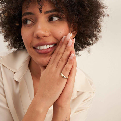 Anillo cúpula burbuja en oro amarillo de 14 quilates llevado por la modelo sonriente, con las manos juntas