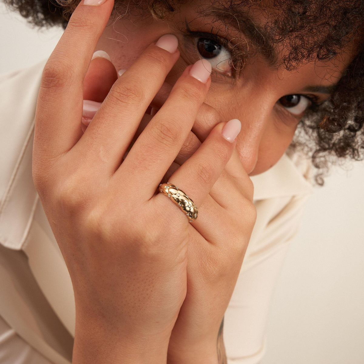 Model mit der Hand vor dem Gesicht, trägt einen Bubble-Kuppelring aus 585er Gelbgold