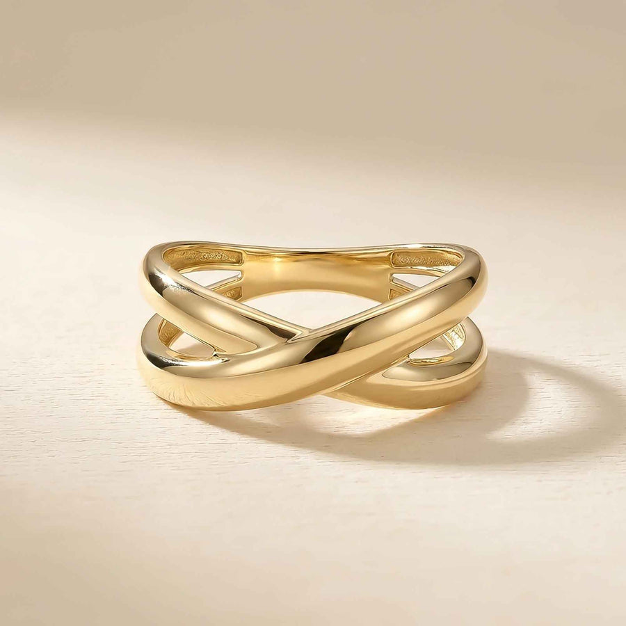 Anillo cruzado en oro amarillo de 14 quilates sobre fondo beige