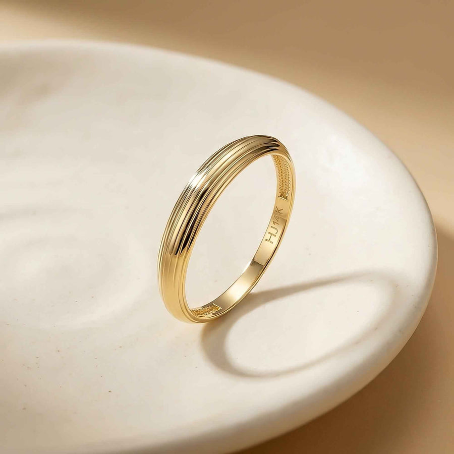 Anillo acanalado en oro amarillo de 14 quilates apoyado en un plato de cerámica blanco
