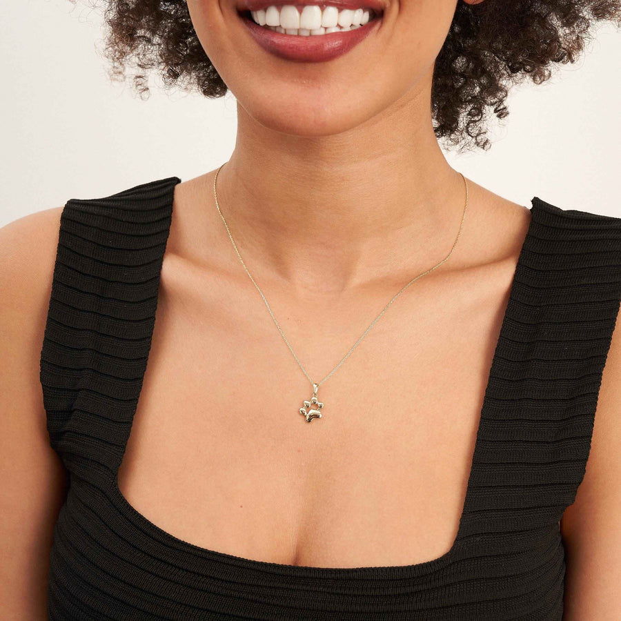 Mannequin souriant en haut noir portant un collier empreinte de patte en or jaune 14 carats