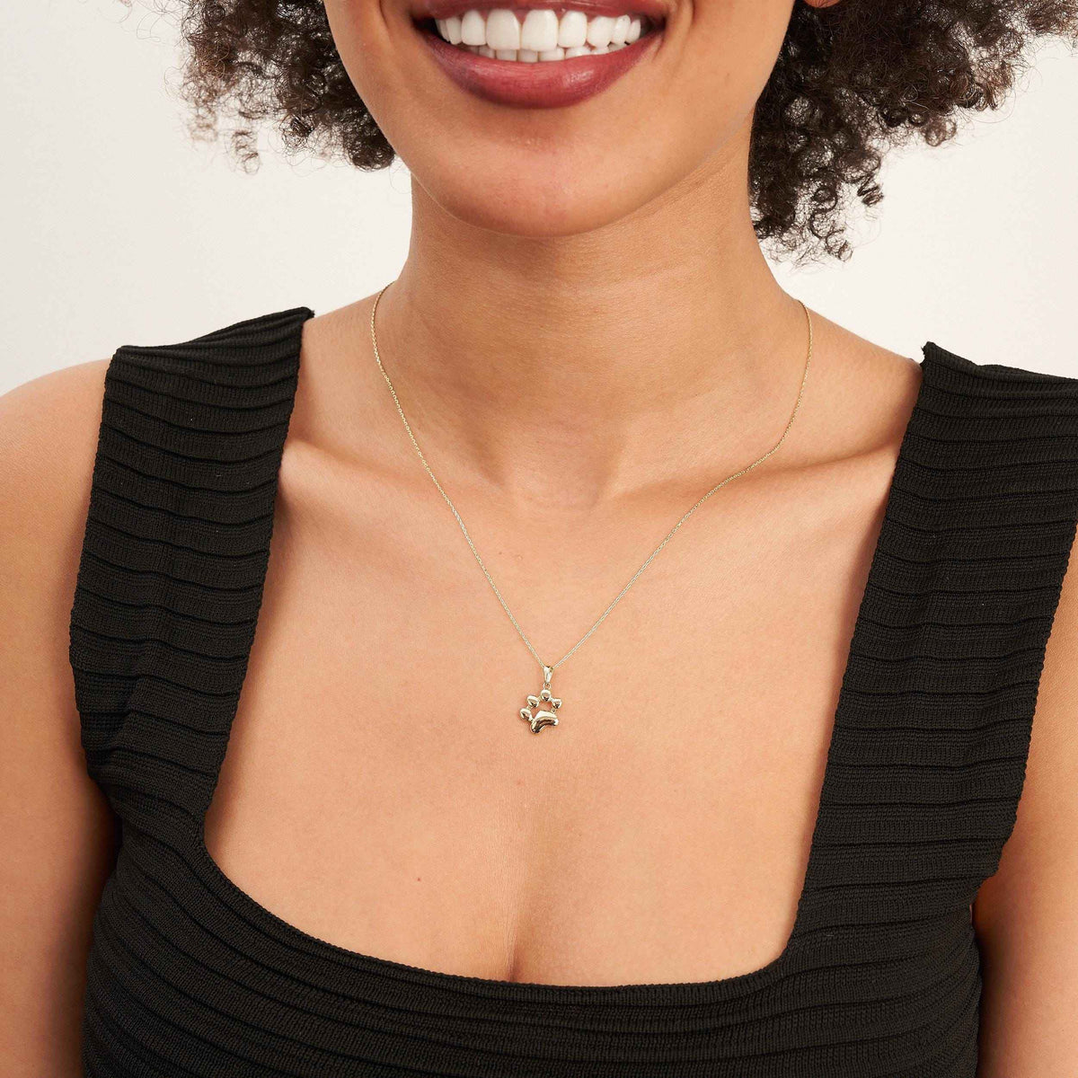 Mannequin souriant en haut noir portant un collier empreinte de patte en or jaune 14 carats