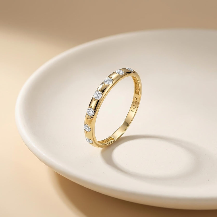 14K yellow gold CZ band ring leaning in a white dish