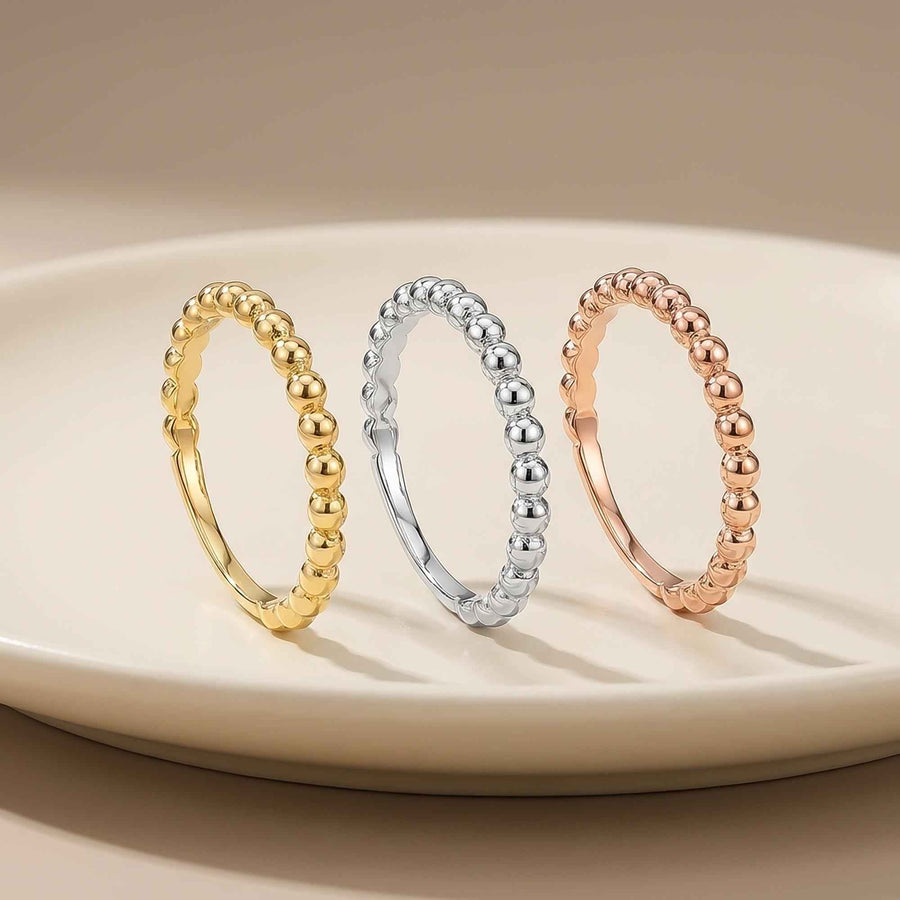 Anillos burbuja en oro amarillo, blanco y rosa de 14 quilates en vertical sobre un plato blanco