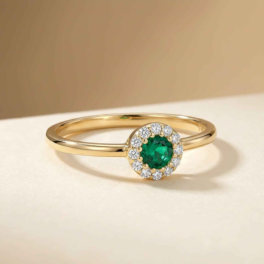Anello halo in oro giallo 14kt con smeraldo creato in laboratorio su sfondo beige