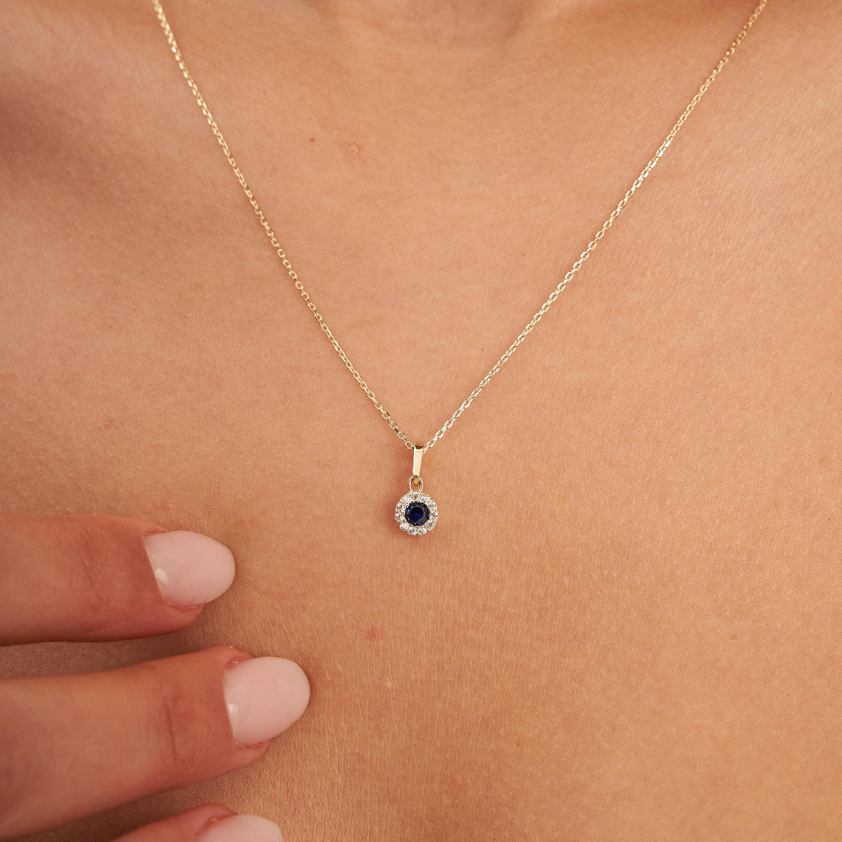 Collier halo saphir rond de synthèse en or jaune 14 carats posé sur la clavicule