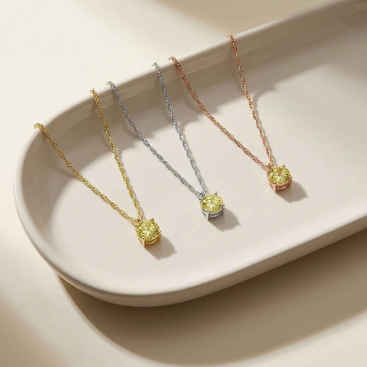 Collares solitarios de citrino en oro amarillo, blanco y rosa de 14 quilates en una bandeja de cerámica
