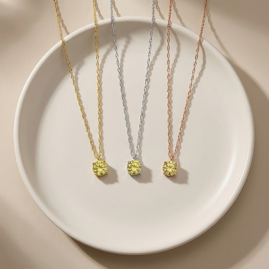 Collares solitarios de citrino en oro amarillo, blanco y rosa de 14 quilates sobre un plato blanco