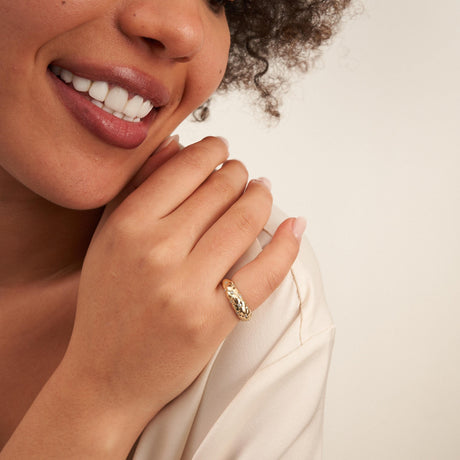 Primer plano del anillo cúpula burbuja en oro amarillo de 14 quilates en el dedo, junto a la sonrisa de la modelo