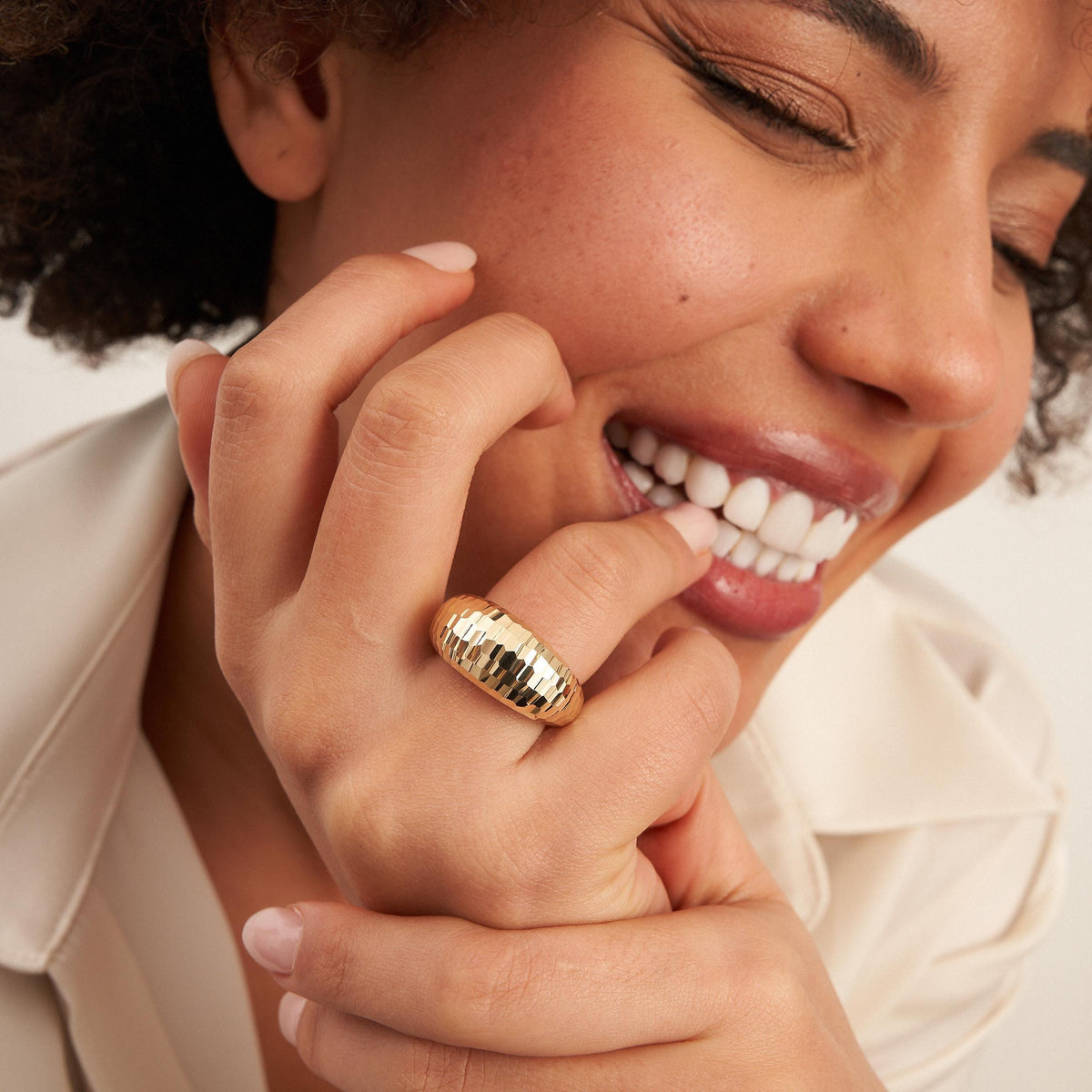 Lachendes Model mit der Hand an den Lippen, trägt einen diamantierten Kuppelring aus 585er Gelbgold