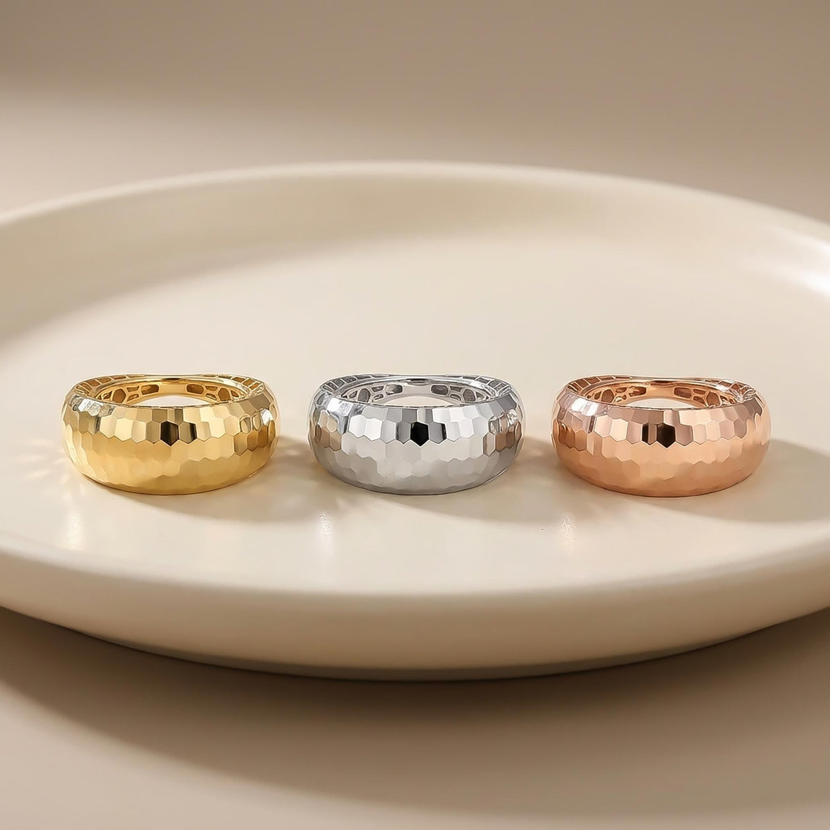 Diamantierte Kuppelringe aus 585er Gelbgold, Weißgold und Roségold auf einem weißen Teller