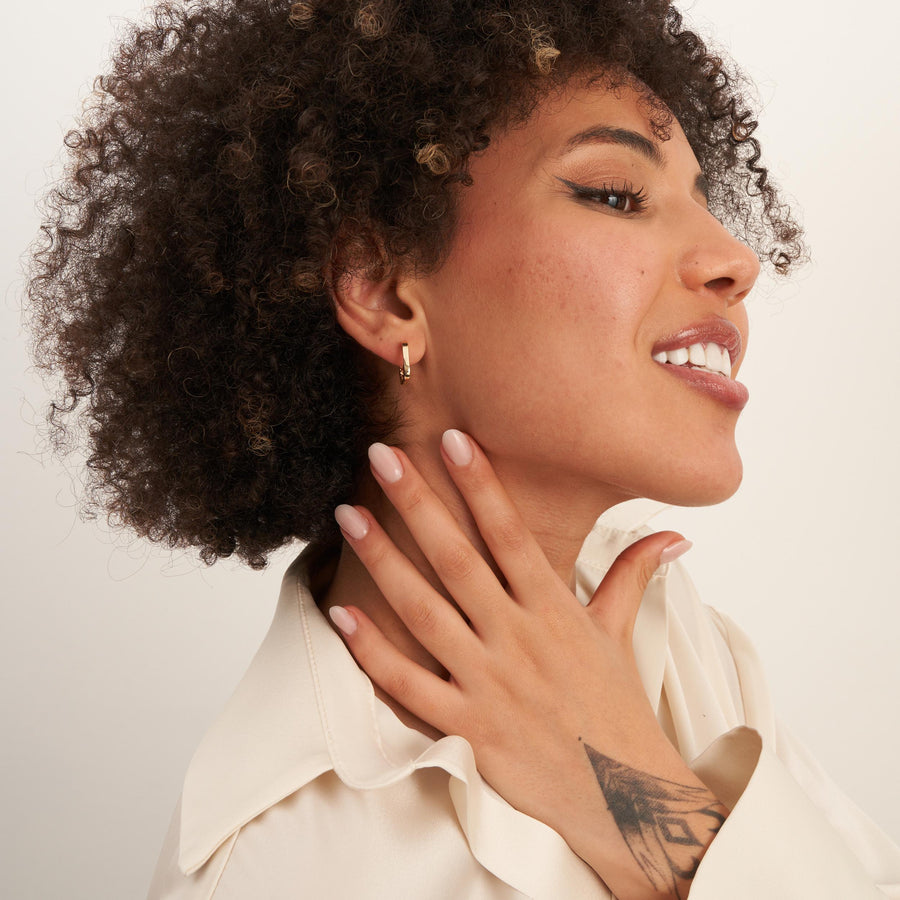 Model in profile with hand at neck wearing 14K yellow gold square hoop earrings