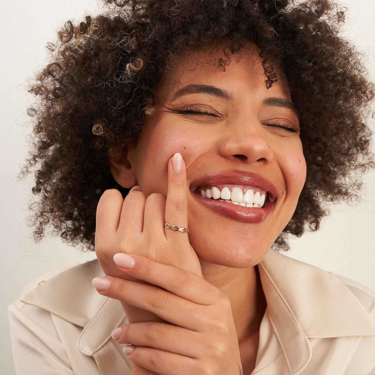 Mannequin souriant, mains au menton, portant une bague infini ajourée en or jaune 14 carats