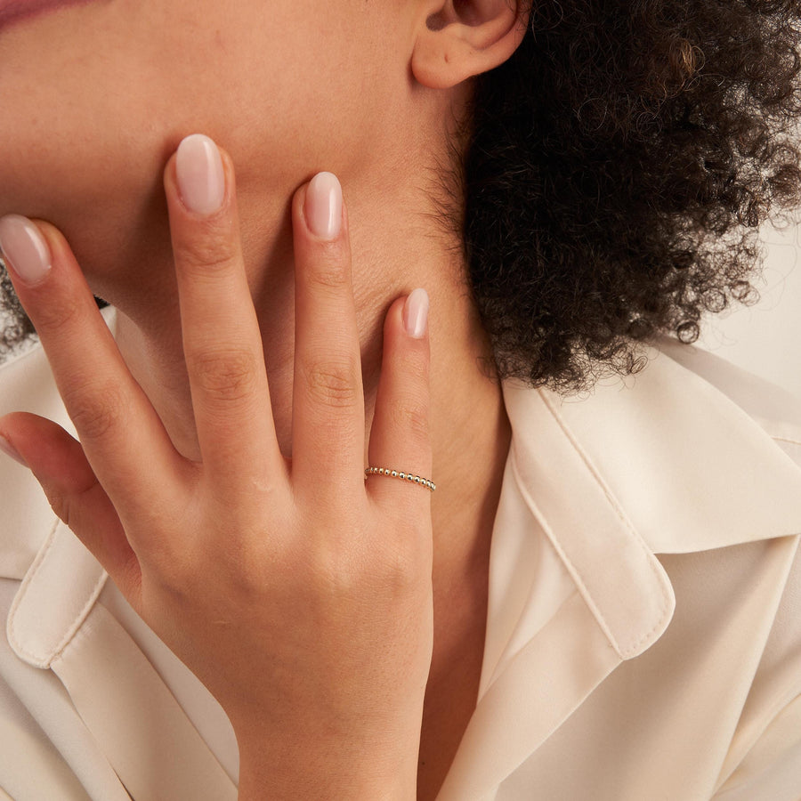Modelo con la mano sobre la boca y un anillo burbuja en oro amarillo de 14 quilates