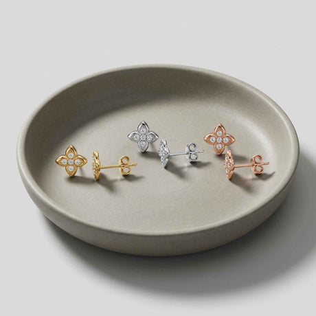 Puces d'oreilles fleur en oxyde de zirconium et or jaune, blanc et rose 14 carats sur une coupelle en céramique grise