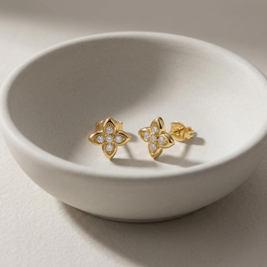 Paire de puces d'oreilles fleur en oxyde de zirconium et or jaune 14 carats dans un bol en céramique