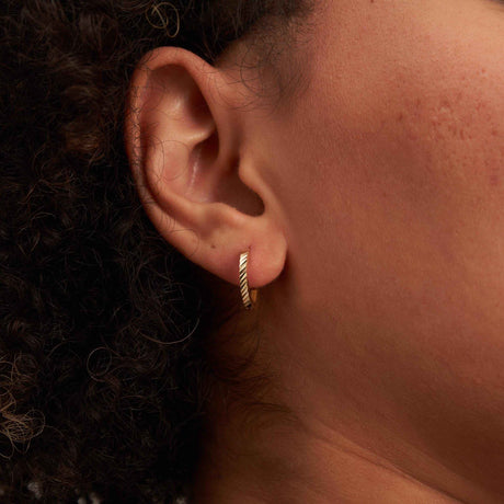 Créole striée taille diamant en or jaune 14 carats portée au lobe, gros plan