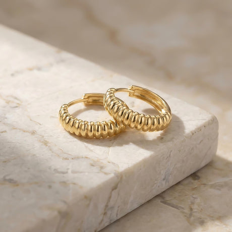 Paire de créoles croissant striées en or jaune 14 carats sur du marbre