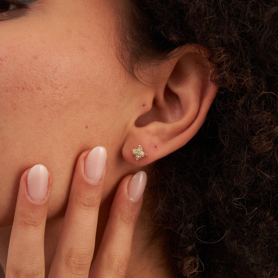 Gros plan d'une oreille portant une puce d'oreille fleur en oxyde de zirconium et or jaune 14 carats