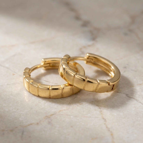 Paire de créoles segmentées en or jaune 14 carats sur du marbre