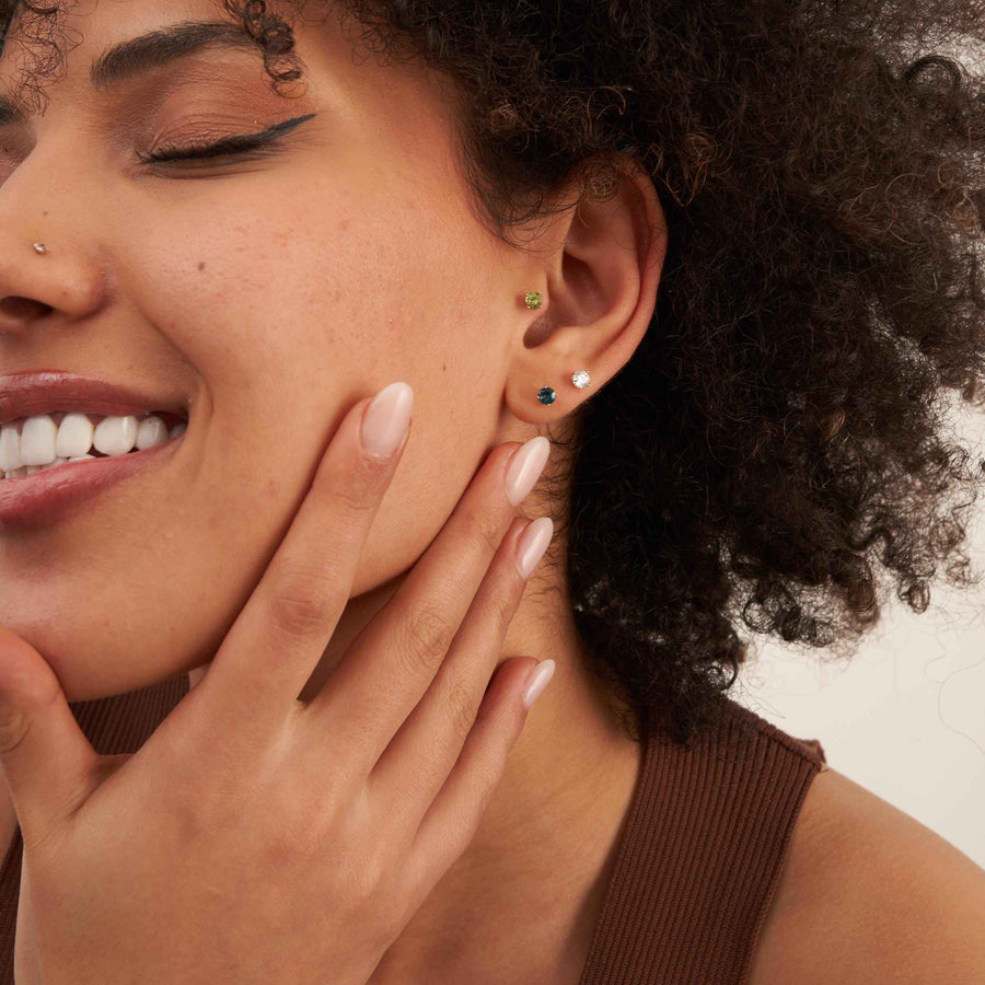 Modella sorridente con gli occhi chiusi che indossa orecchini a lobo con pietra da 4 mm in oro giallo 14kt