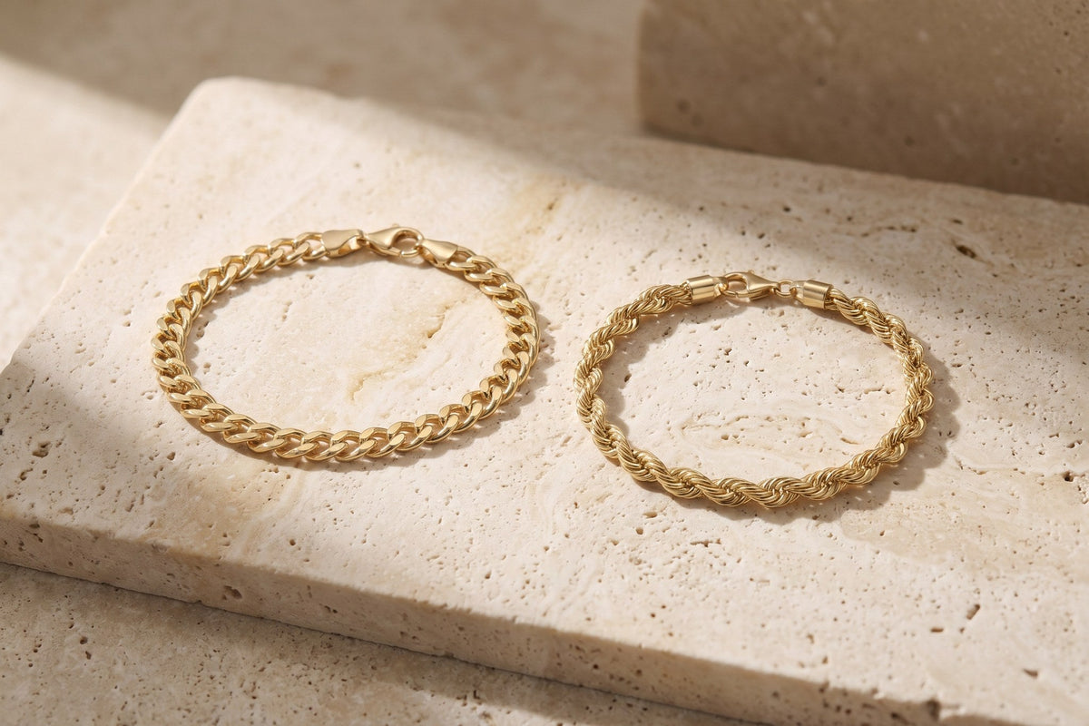 Heon 14K gold Cuban link bracelet and rope chain bracelet side by side on travertine