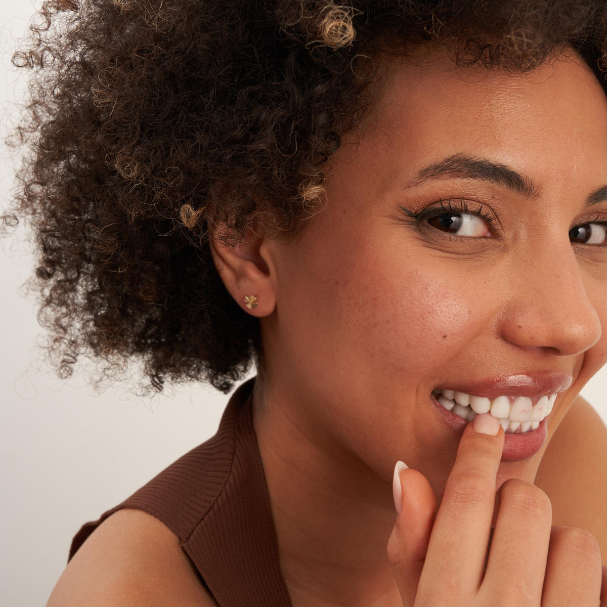 Model wearing 14K gold four-leaf clover stud earrings