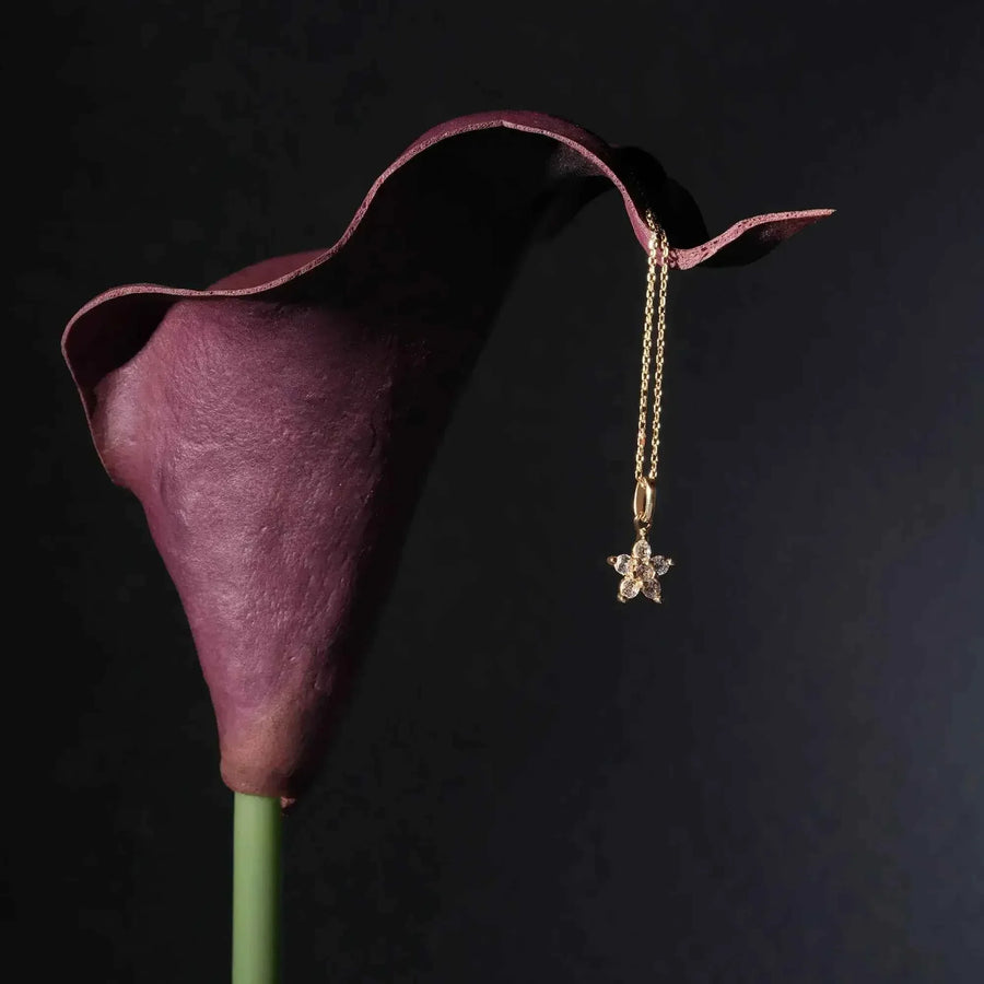 Collana con ciondolo fiore a stella con zirconi in oro giallo 14kt appesa a una calla viola