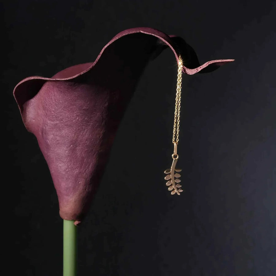Collier pendentif branche d'olivier en or jaune 14 carats suspendu à un calla violet sur fond noir