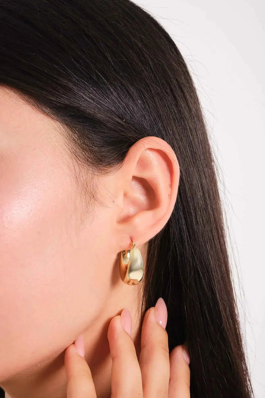Tropfen-Creole aus 585er Gelbgold am Ohr, Model mit den Fingern am Kinn